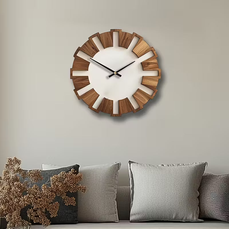 Wooden wall clock on a neutral wall with decorative pillows below.