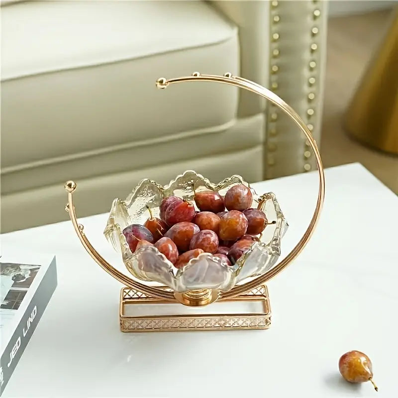Decorative glass bowl with gold rim filled with grapes on a white surface.