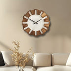 Wooden wall clock on a beige wall above a sofa with decorative branches.
