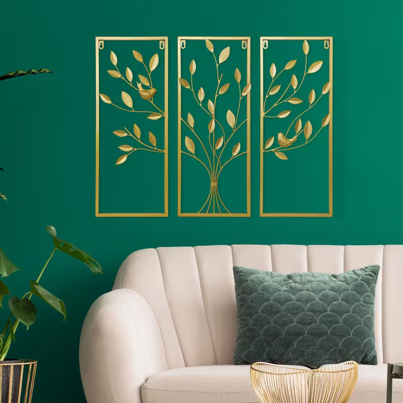 Decorative wall art with gold leaf patterns on a teal wall above a beige sofa.