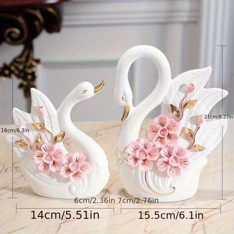 Decorative swan figurines with floral details and measurements on a marble surface.