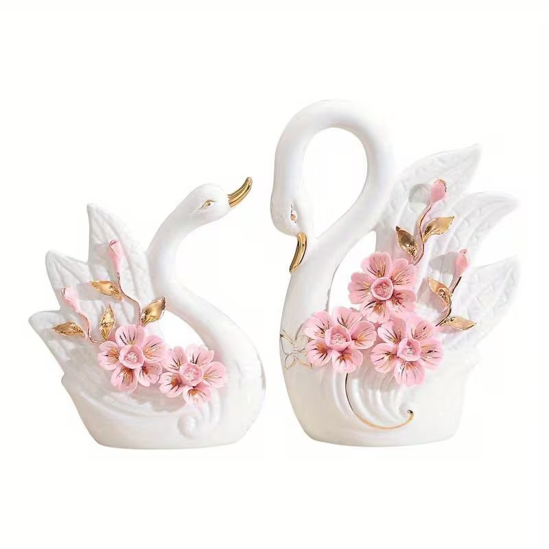 Two decorative swan figurines with floral details on a white background