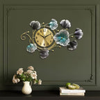 Decorative wall clock with floral designs on a dark green wall.