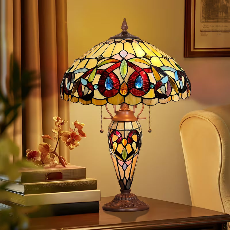 Stained glass lamp on a table with books and decorative items in a warm-toned room.