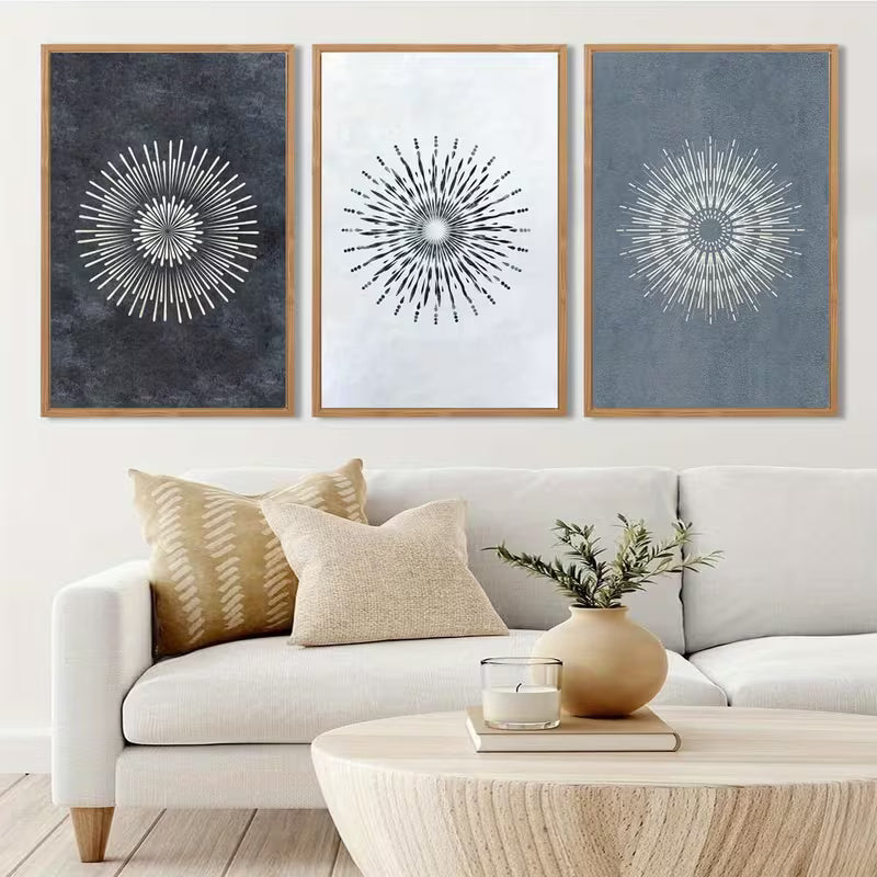 Living room with a white sofa, decorative pillows, a coffee table with a plant and candle, and wall art with starburst designs.