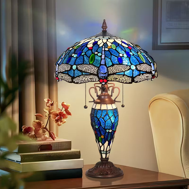 Tiffany-style stained glass lamp on a table with decorative books and flowers.