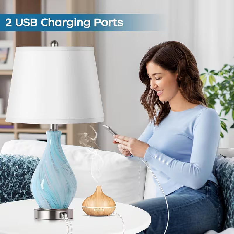 Woman using a smartphone with two USB charging ports visible, one on a lamp and one on a small device.