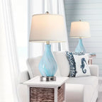Two table lamps with blue glass bases on a white side table in a living room setting.