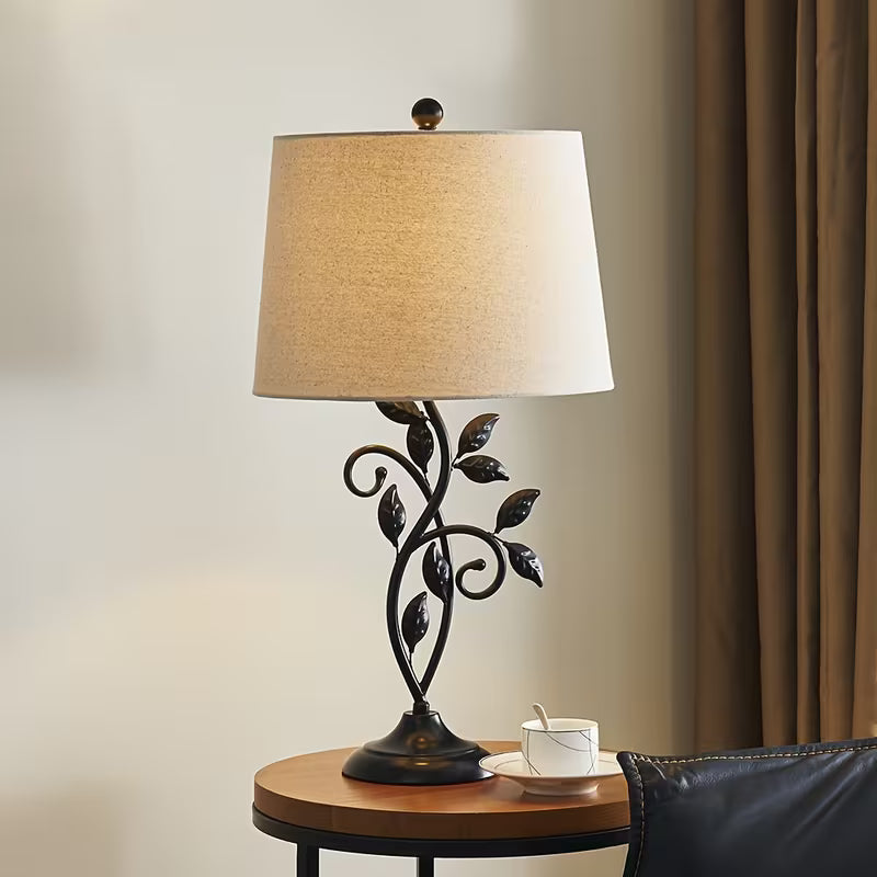 Decorative table lamp with leaf design on a side table next to a sofa.