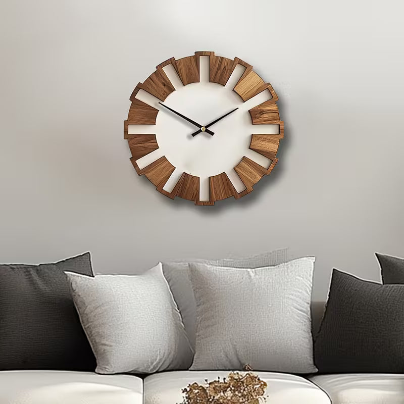 Wooden wall clock on a neutral wall above a sofa with cushions.
