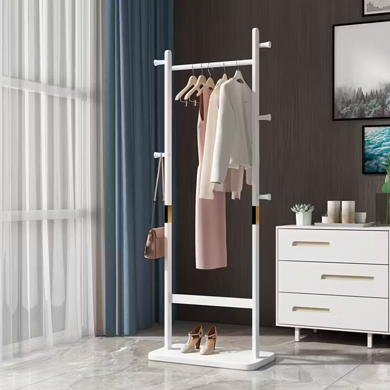 White freestanding coat rack with clothes in a room with a dresser and window.