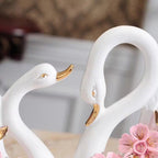 Two white swan figurines with gold accents on a blurred background