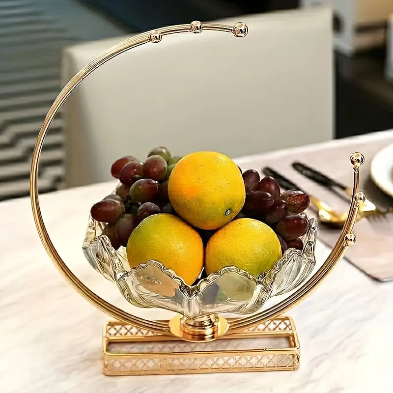 Decorative glass fruit bowl with gold rim and base on a table.