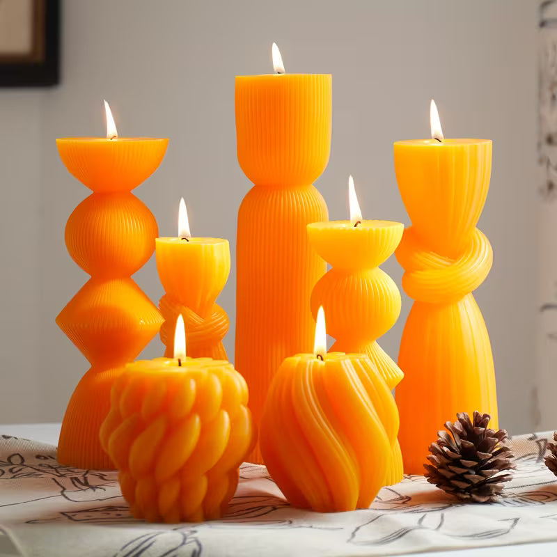 Set of orange candles with unique designs on a table.