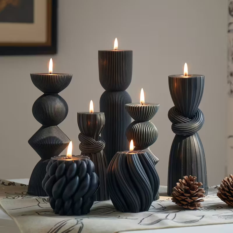 Set of black textured candle holders with lit candles on a table.